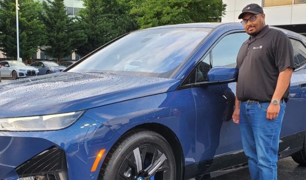 Photo of DJ standing next to a blue car